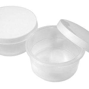 May include: Two white plastic containers with lids. The containers are round and have a smooth surface. The lids are also round and have a smooth surface. The containers are empty.
