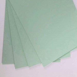 Puede incluir: Una pila de cinco hojas de papel verde claro.