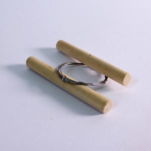 May include: Two wooden dowels with a coil of silver wire wrapped around them.