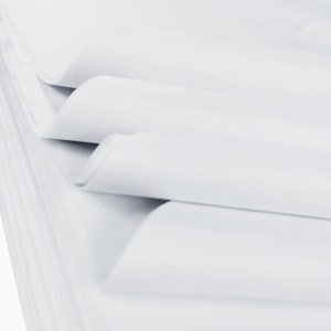 May include: A stack of white paper sheets, folded and layered, creating a smooth, textured surface.