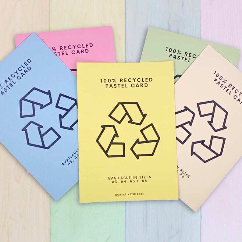 May include: A collection of pastel-colored recycled paper cards. Each card features a black recycling symbol and the text "100% Recycled Pastel Card." Available in sizes A3, A4, A5, and A6. The cards are arranged on a multicolored wooden surface.