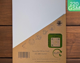 Könnte beinhalten: Ein weißes Kartonblatt mit brauner Papierunterseite. Die Unterseite hat einen Barcode, Text mit der Aufschrift "Recycled White Card A5 280 micron" und eine Website-Adresse. Die Unterseite hat auch einen QR-Code und den Text "What's waiting for you?"