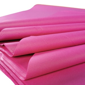 May include: Pink tissue paper folded in a stack. The paper is a bright, vibrant pink colour.