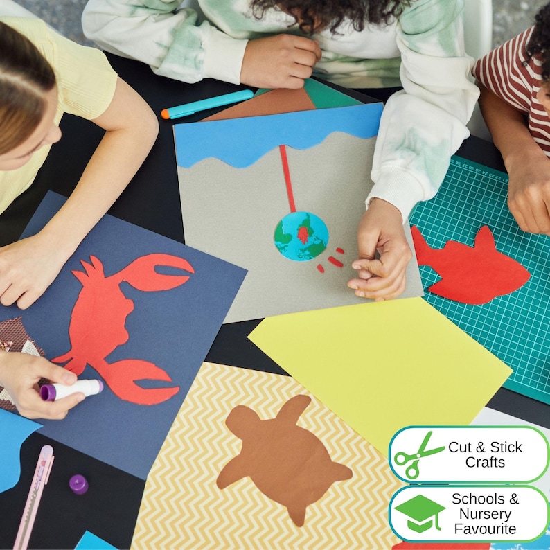 May include: A collection of paper craft projects featuring a red crab cutout on dark blue paper, a brown turtle on chevron paper, a red fish on a green cutting mat, and a globe illustration on grey paper with the text Cut & Stick Crafts.