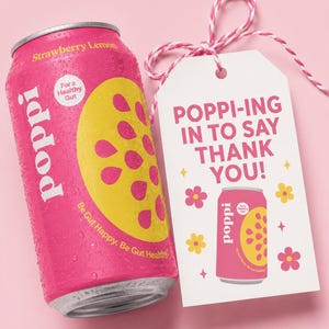 May include: A pink Strawberry Lemon Poppi can with a yellow lemon slice design and the text "Be Gut Happy. Be Gut Healthy." A white tag reads "Poppi-ing in to say thank you!" with flower and star graphics.