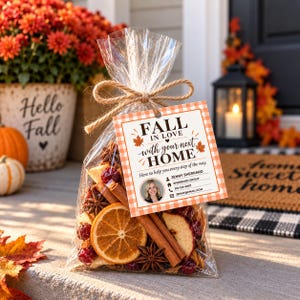 Può includere: Un sacchetto regalo trasparente riempito con fette di arancia essiccate, bastoncini di cannella, anice stellato e mirtilli rossi. Un'etichetta quadrata con bordo a quadretti arancioni riporta: FALL IN LOVE WITH YOUR NEXT HOME, Jenny Sherrard, Sherrard Group, 515-123-4567.