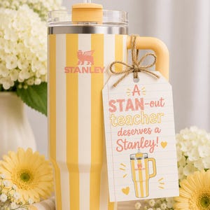 Può includere: Un bicchiere Stanley a righe gialle e bianche con manico e cannuccia. Il bicchiere ha il logo Stanley e un'etichetta regalo con la scritta "A STAN-out teacher deserves a Stanley!" con un disegno del bicchiere.