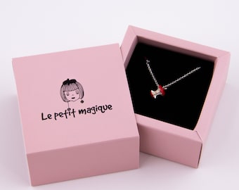 May include: A pink gift box with a silver necklace inside. The necklace features a red apple core charm. The box has the text "Le petit magique" printed on the top.