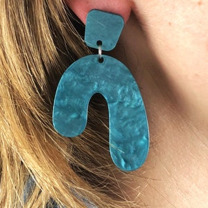 Puede incluir: Pendientes de declaración de color azul turquesa con una forma geométrica. Los pendientes están hechos de un material marmoleado y tienen un diseño único.