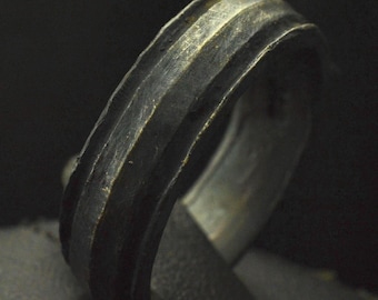 May include: A silver-toned metal ring with a ridged design. The ring is worn and has a dark patina.