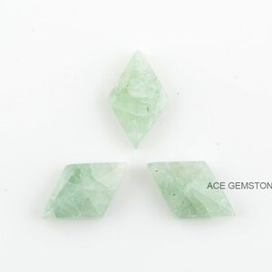 May include: Three green gemstone kite-shaped cabochons on a white background. ACE GEMSTONE is printed in the bottom right corner of the image.
