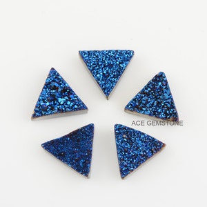 May include: Five blue triangular gemstone cabochons with a sparkly, iridescent finish.  The cabochons are arranged in a circle on a white background.  ACE GEMSTONE is printed in black text on the white background.