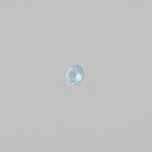 May include: A light blue round gemstone with facets.