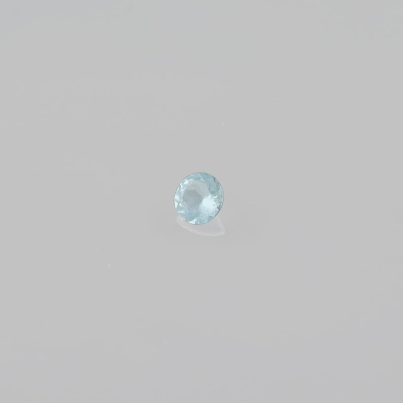 May include: A light blue round gemstone with facets.