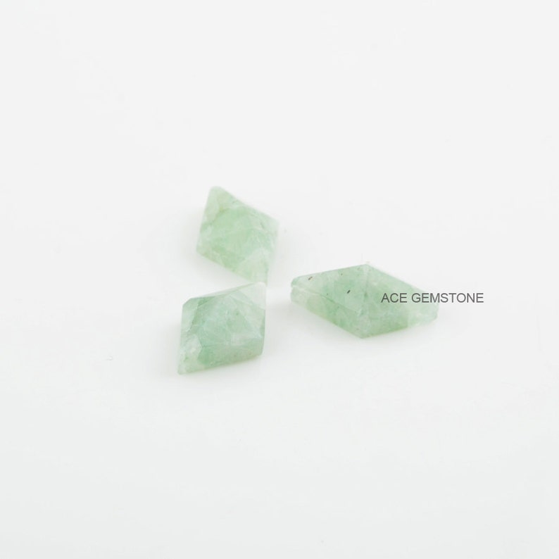 May include: Three light green gemstone beads in a diamond shape. ACE GEMSTONE is printed on the white background.