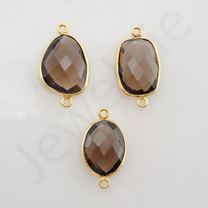 May include: Three gold-toned gemstone connector charms with a faceted smoky quartz stone. The charms are in the shapes of an oval, a rectangle, and a freeform shape.