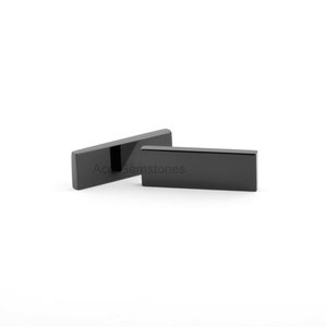 May include: Two black rectangular obsidian stones, one slightly larger than the other, are displayed on a white surface. The stones are smooth and polished.