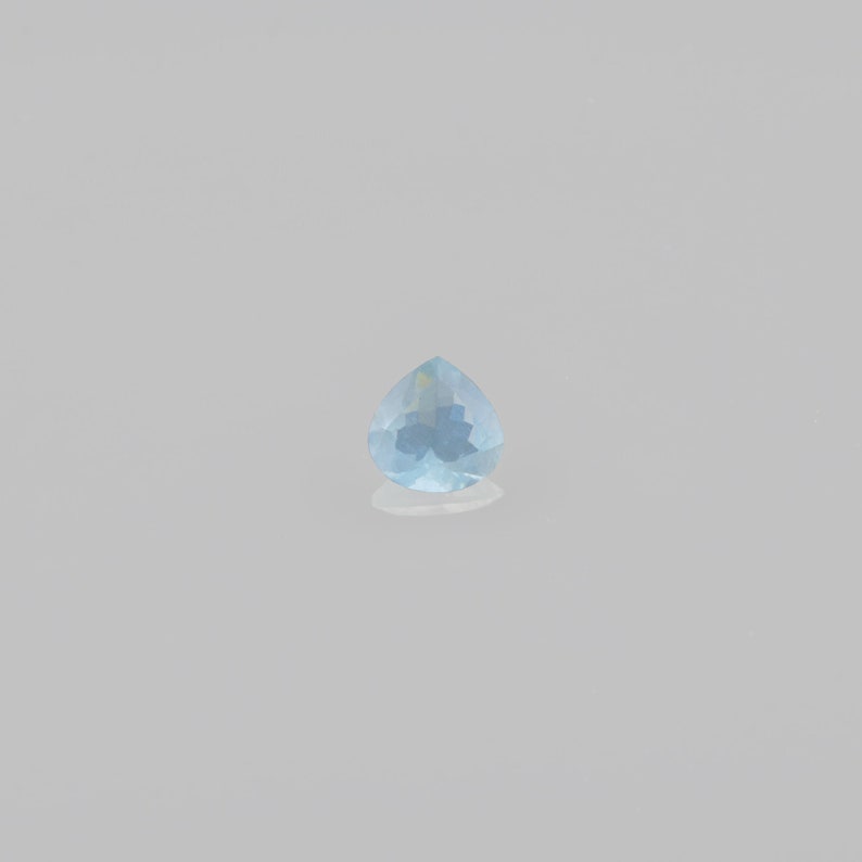 May include: A light blue teardrop-shaped gemstone with facets.
