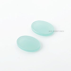May include: Two oval-shaped, light blue cabochon gemstones. The gemstones are smooth and translucent.