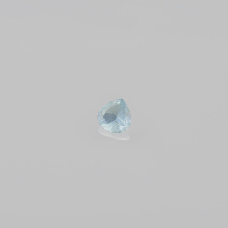 May include: A light blue pear-shaped gemstone with a faceted cut.