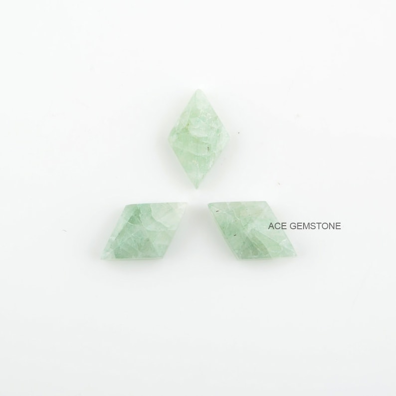May include: Three green gemstone kite-shaped cabochons on a white background. ACE GEMSTONE is printed in the bottom right corner of the image.