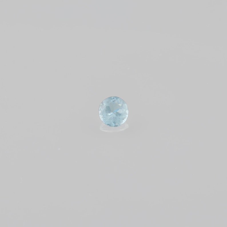 May include: A light blue aquamarine gemstone, round in shape, with a faceted cut.