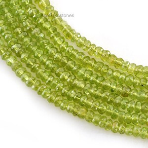 May include: A strand of light green peridot beads. The beads are faceted and have a slightly irregular shape. The beads are strung on a clear thread.