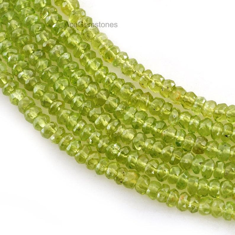 May include: A strand of light green peridot beads. The beads are faceted and have a slightly irregular shape. The beads are strung on a clear thread.