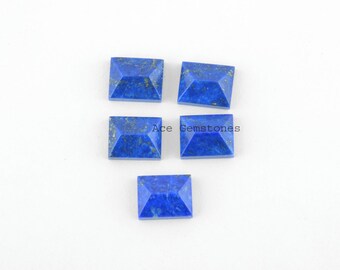 May include: Five blue lapis lazuli cabochons with gold flecks. The cabochons are rectangular with a pyramid shape.  Ace Gemstones is printed on the white background.