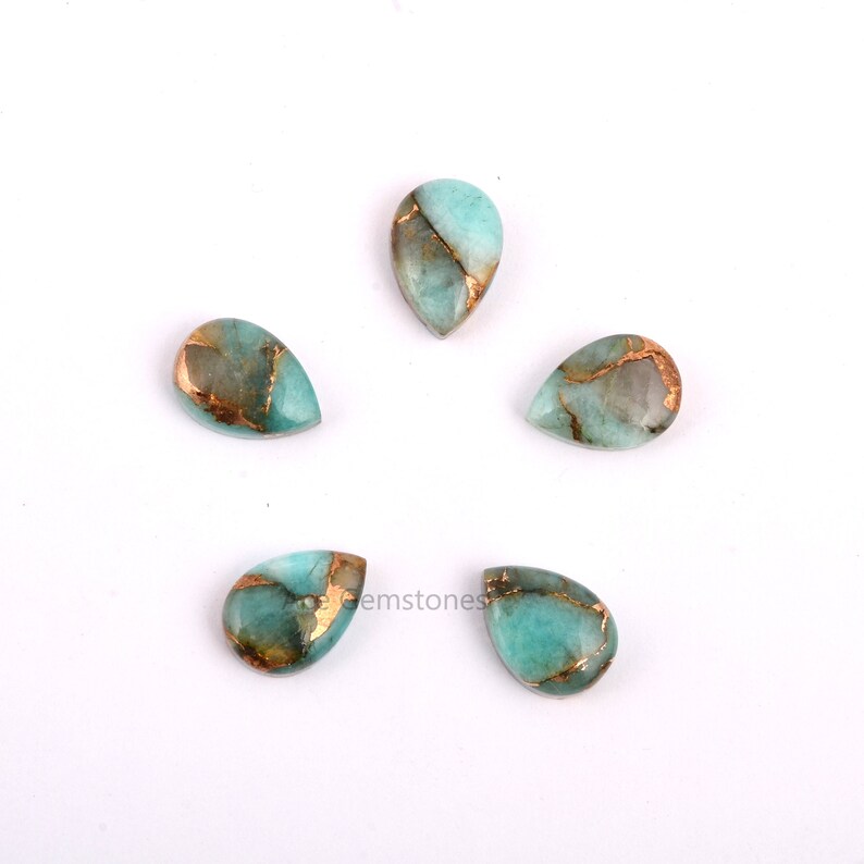 May include: Five teardrop-shaped gemstones with a light blue and gold color pattern. The gemstones are arranged in a circle on a white background.
