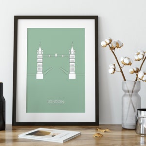 May include: A framed print of a minimalist illustration of the Tower Bridge in London, with a green background and the word "LONDON" printed below the bridge.