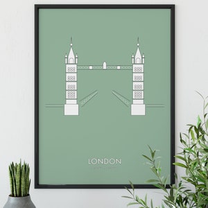 May include: A framed print with a minimalist line drawing of the Tower Bridge in London on a sage green background. The text "LONDON" and "Tower Bridge" is printed below the image.