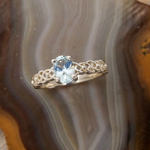 May include: A silver ring with a light blue oval gemstone set in a Celtic knot design.