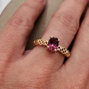 Puede incluir: Un anillo de oro con una banda trenzada y una gran piedra preciosa ovalada de color p&uacute;rpura.