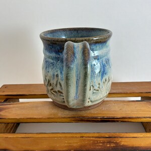 Pu&ograve; includere: Tazza in ceramica fatta a mano con superficie strutturata e manico unico. La tazza presenta una miscela di smalto blu, marrone e bianco, creando un effetto marmorizzato. La tazza &egrave; alta circa 10 cm e ha un diametro di 9 cm, perfetta per caff&egrave; o t&egrave;.