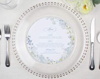May include: A white round menu card with a blue floral design. The menu card has the words "Menu", "Salad", "Entree", and "Wedding Cake" printed on it.