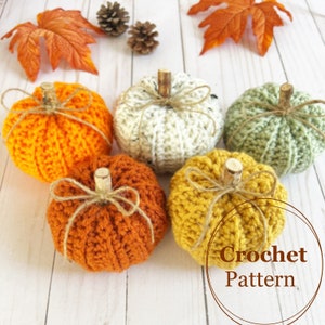 Op de afbeelding: Vijf gehaakte pompoenen in verschillende kleuren, waaronder oranje, wit, groen, bruin en geel. De pompoenen zijn gerangschikt op een wit houten oppervlak. De tekst "Crochet Pattern" is zichtbaar in de rechterbenedenhoek van de afbeelding.