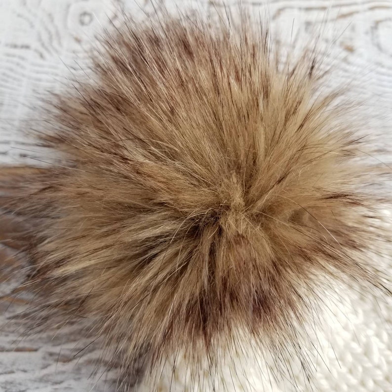 May include: A fluffy brown faux fur pom pom for a hat. The pom pom is made of soft, synthetic fur and is perfect for adding a touch of warmth and style to any winter hat.
