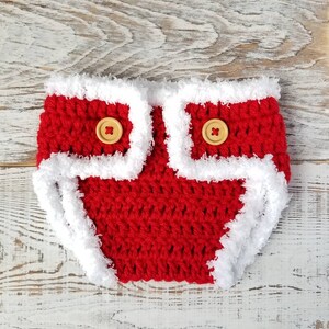 Pu&ograve; includere: Copertura per pannolino per neonato in crochet rosso con bordino in pelliccia bianca e due bottoni in legno.