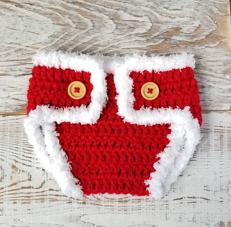 Pu&ograve; includere: Copertura per pannolino per neonato in crochet rosso con bordino in pelliccia bianca e due bottoni in legno.