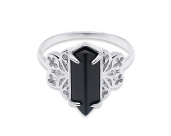 May include: A silver ring with a black gemstone in the center. The gemstone is a rectangular shape with pointed ends. The ring has a delicate, filigree design on the sides.