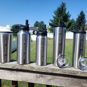 May include: Five stainless steel water bottles with different sizes and labels. The bottles are arranged from left to right: 25oz Shaker Bottle, 32oz Sports Bottle, 18oz Sports Bottle, 30oz Skinny Duo, 20oz Skinny Duo.