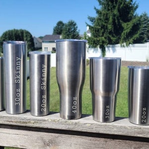 May include: A set of eight stainless steel tumblers in various sizes, ranging from 12 oz to 40 oz. The tumblers are all silver and have different size labels on them, including "12oz", "20oz", "30oz", "20oz Skinny", "30oz Skinny", "40oz", and "30oz Thick".