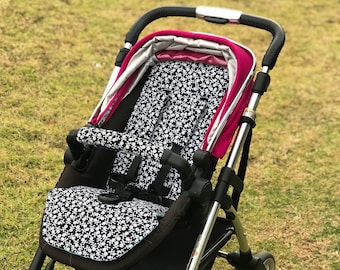 May include: A black stroller with a pink canopy and a black and white patterned seat. The stroller has a silver frame and black wheels.