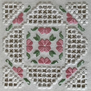 Könnte beinhalten: Weißer Stoff mit einem sich wiederholenden Muster aus rosa Blüten und grünen Blättern. Der Stoff ist mit einem Gittermuster gestickt.