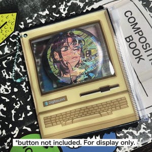 May include: A clear acrylic charm in the shape of a vintage computer. The screen displays a holographic image of an anime-style character. The text "DigitaLove" is on the bottom left. The text "THE GUY SHE WAS INTERESTED IN WASN'T A GUY AT ALL" is on the image.