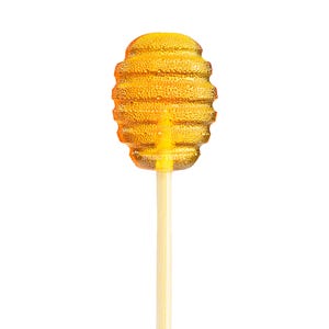 May include: A honey-flavored lollipop shaped like a beehive. The amber-colored candy has a textured surface and is mounted on a light-colored wooden stick. The text "Sparko Sweets" is visible on the lollipop.