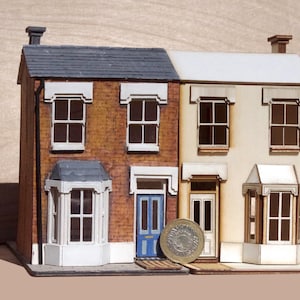 May include: A miniature model of a two-story, brick row house with a blue door and white trim. The model is made of wood and has a detailed exterior.