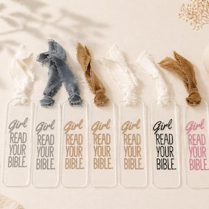 Peut inclure: Marque-pages en acrylique transparent avec l'inscription "Girl Read Your Bible" en différentes couleurs. Chaque marque-page est orné d'un ruban ou d'un tissu de couleur différente en haut. Les couleurs incluent le blanc, le bleu et le marron.