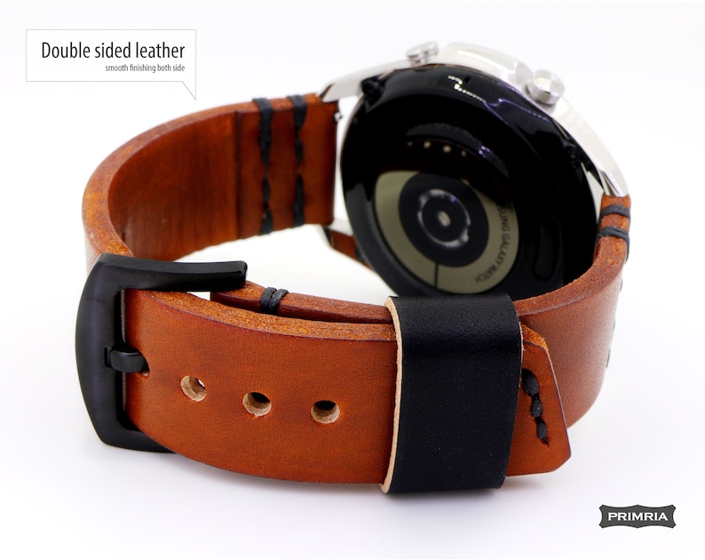 May include: A brown leather watch band with black stitching and a black buckle. The band is double-sided, meaning it has the same smooth finish on both sides. The band is shown attached to a silver smartwatch.
